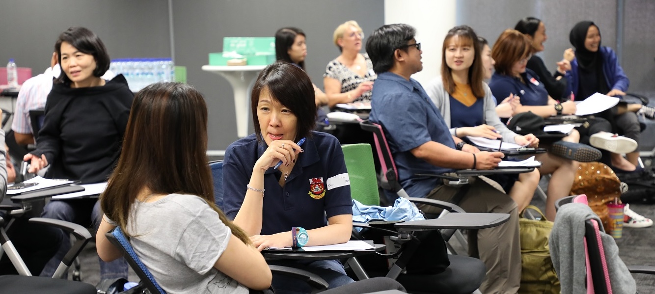 Two ladies in a discussion in a room of other people